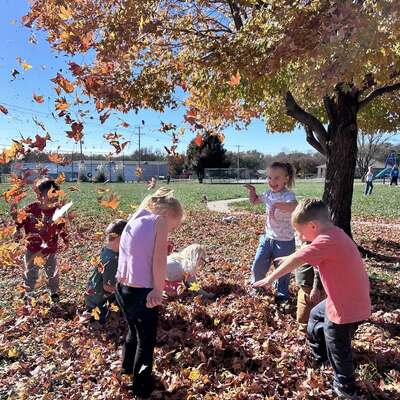 Early Learning playing in fall leaves
