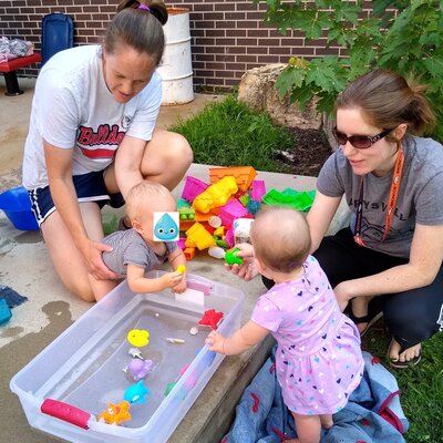 Babies and their caregivers get wet at a summer library program.